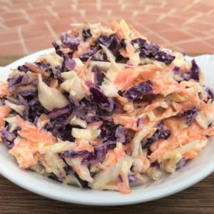 Healthy coleslaw in white dish on tiled table