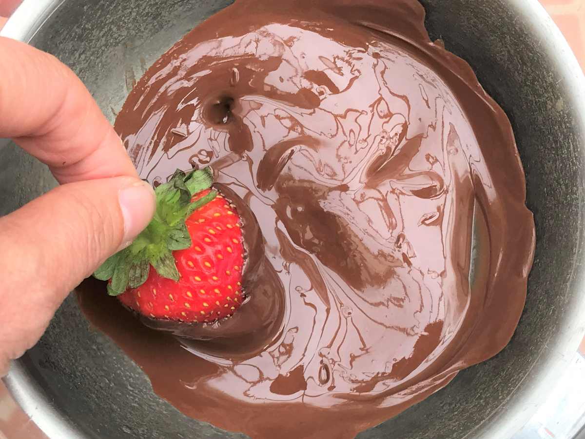 Dipping strawberries in dark chocolate.