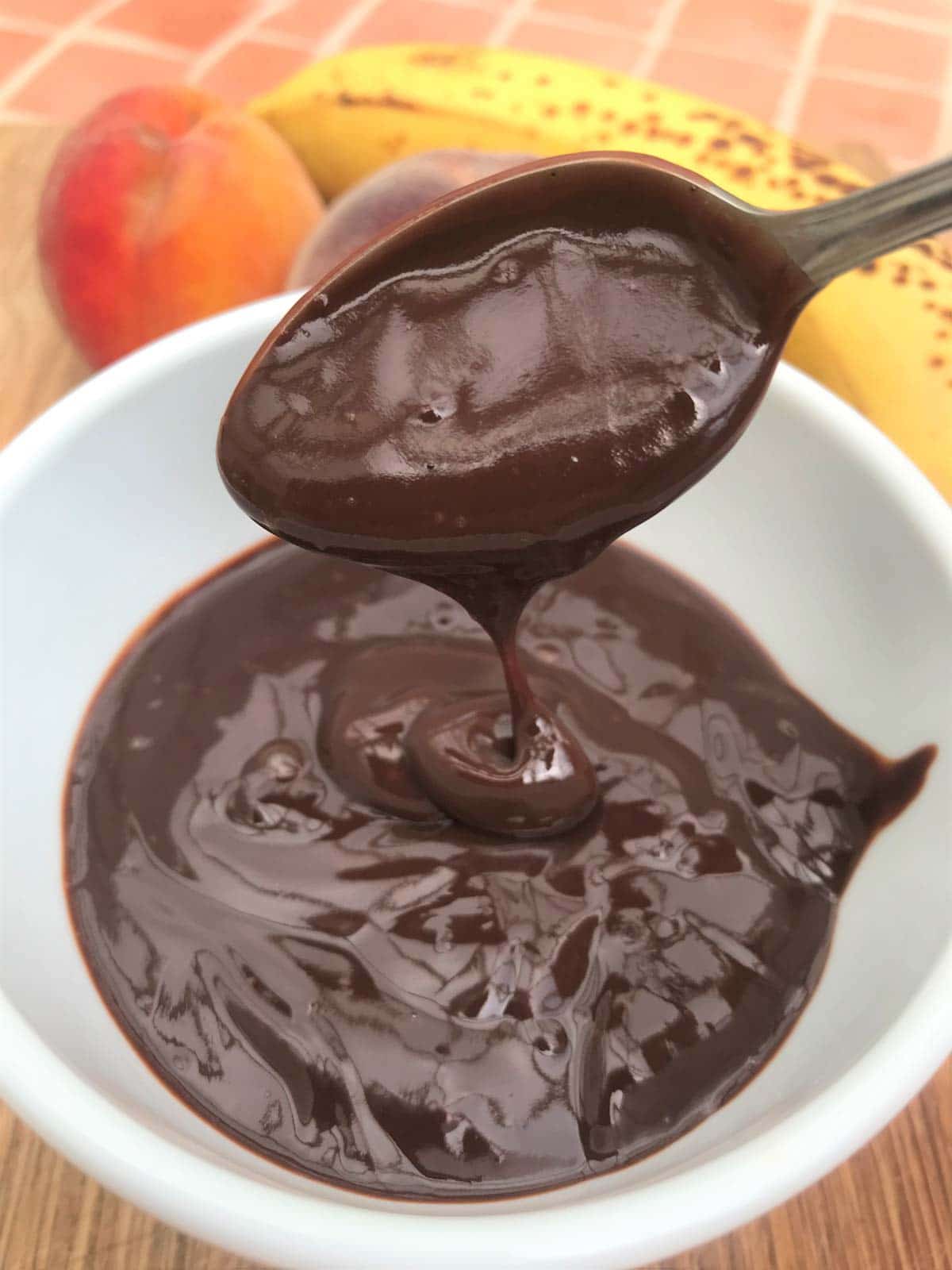 Healthy chocolate sauce on spoon with fruit