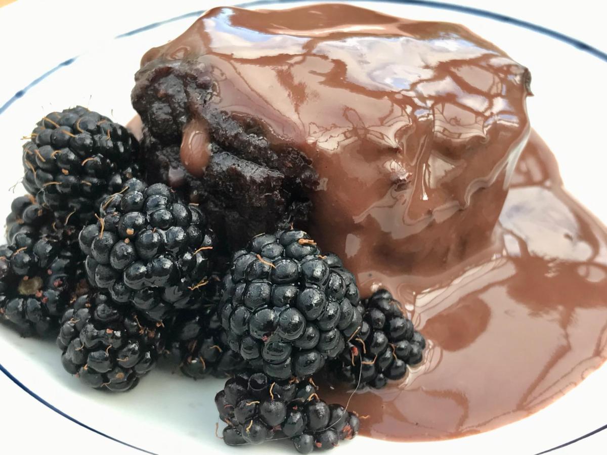Gluten free chocolate muffins with chocolate sauce and blackberries