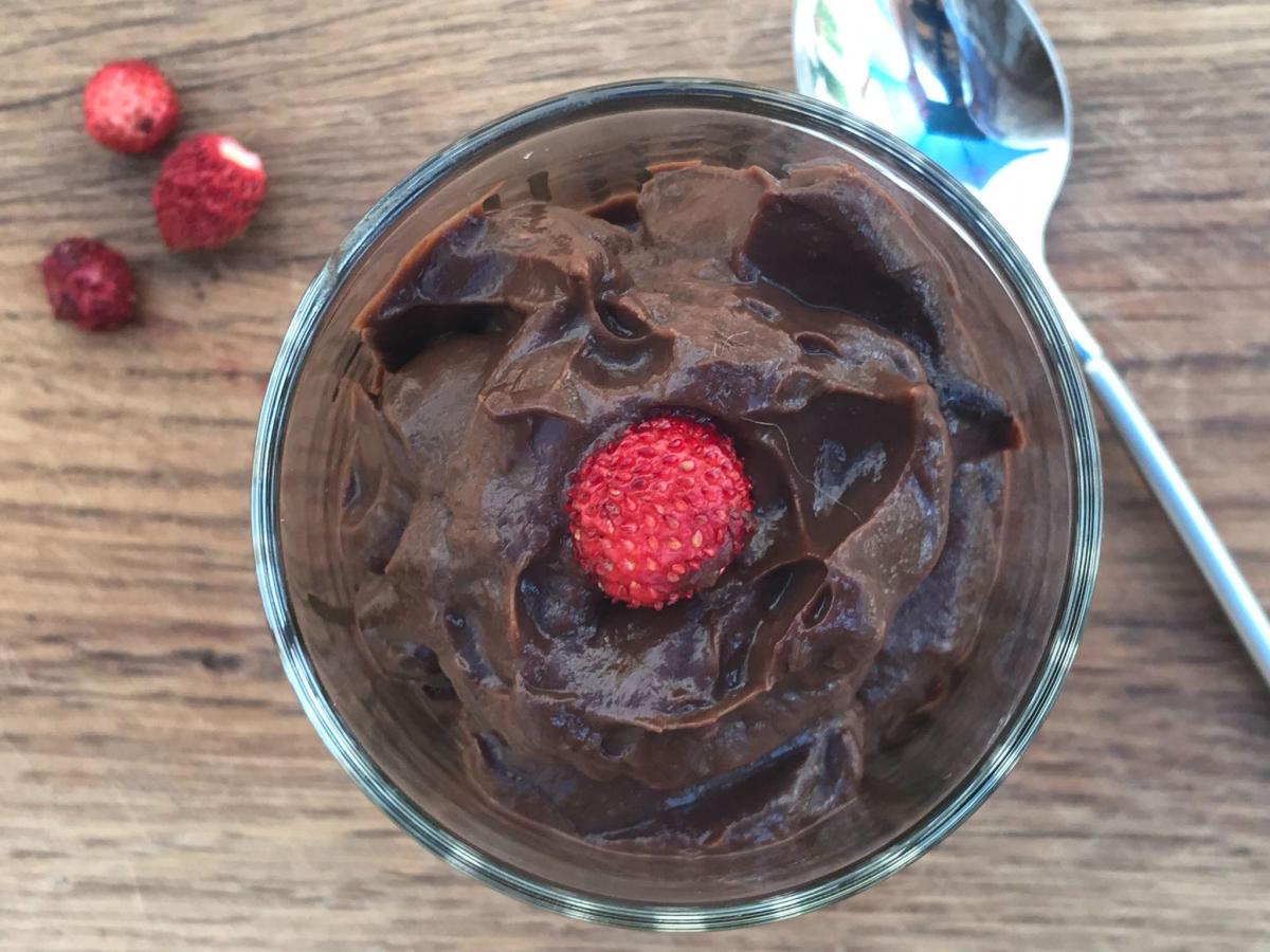 Avocado chocolate mousse in glass with spoon and berries.
