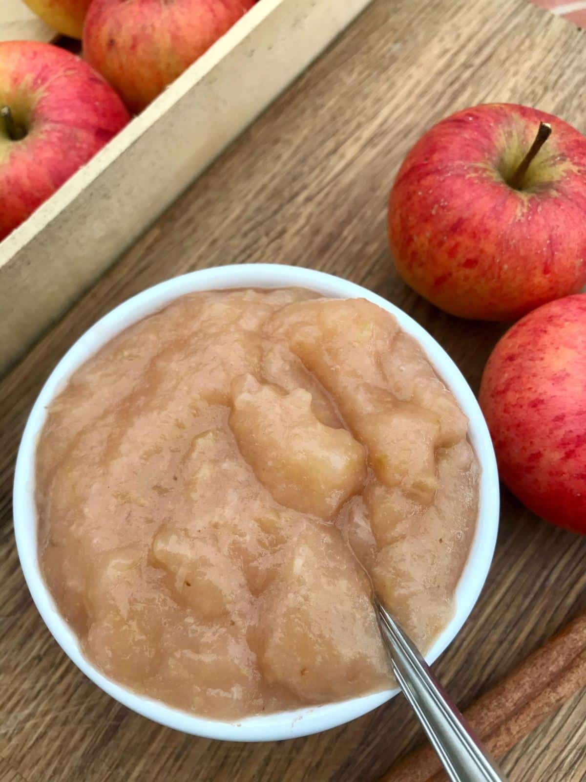 Bowl of unsweetened slow cooker apple puree with apples.