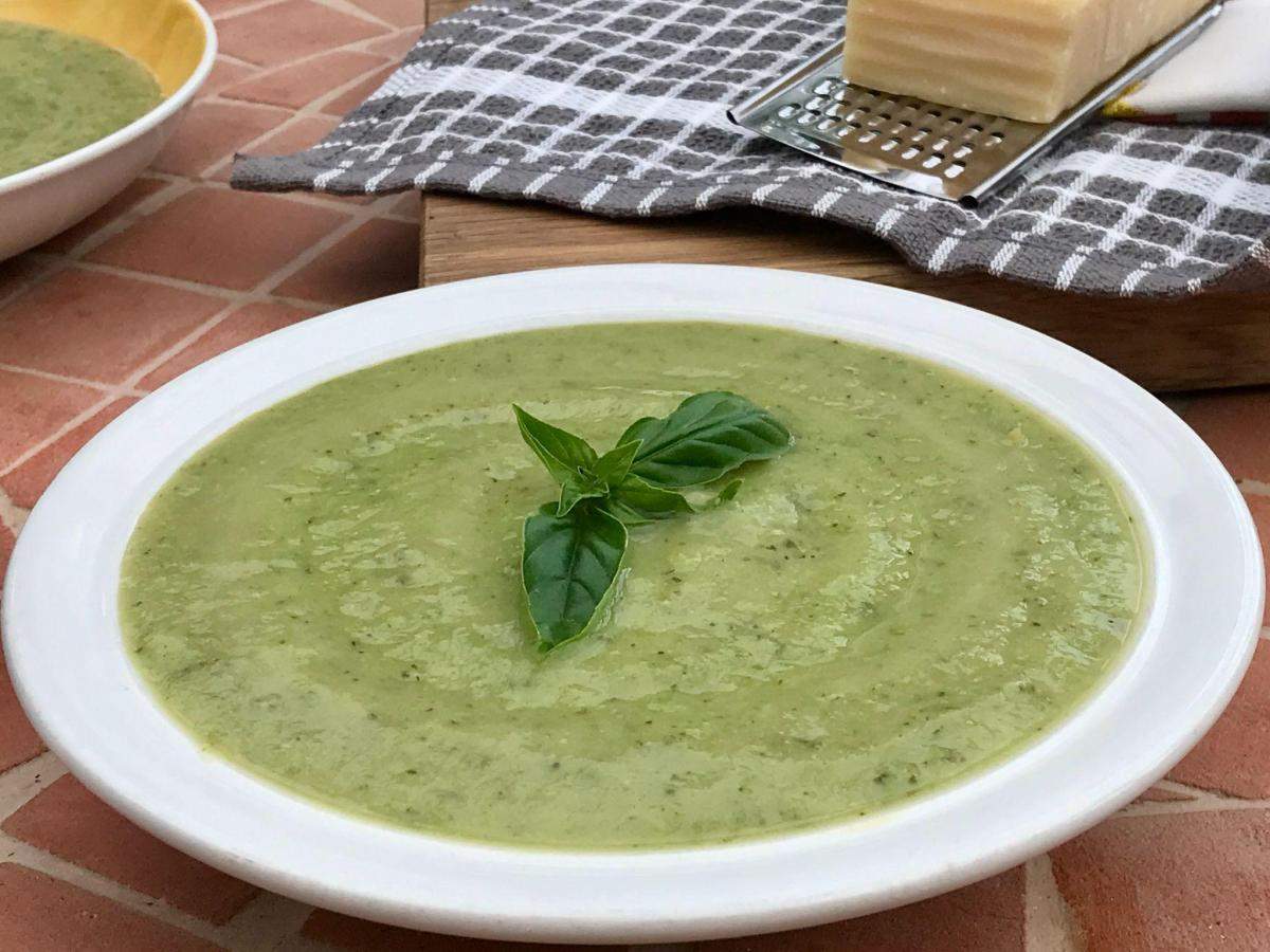 Pea and courgette soup in white bowl with checked cloth