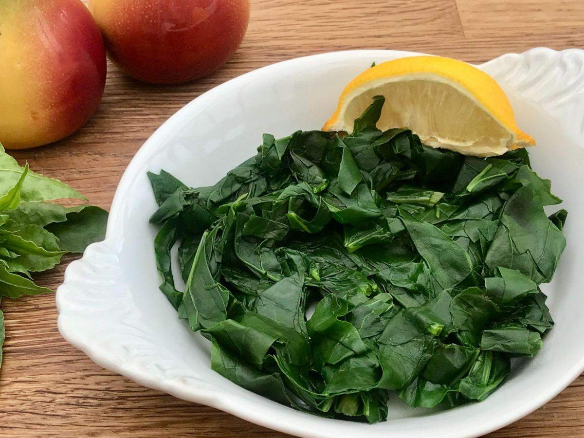Cooked perpetual spinach in white dish.