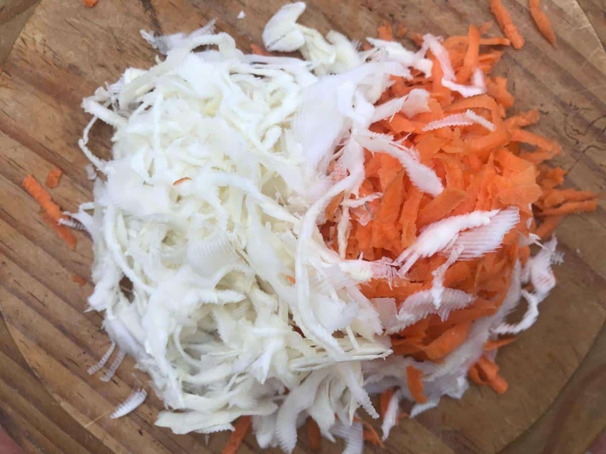 Grated carrot and cabbage on wooden board.
