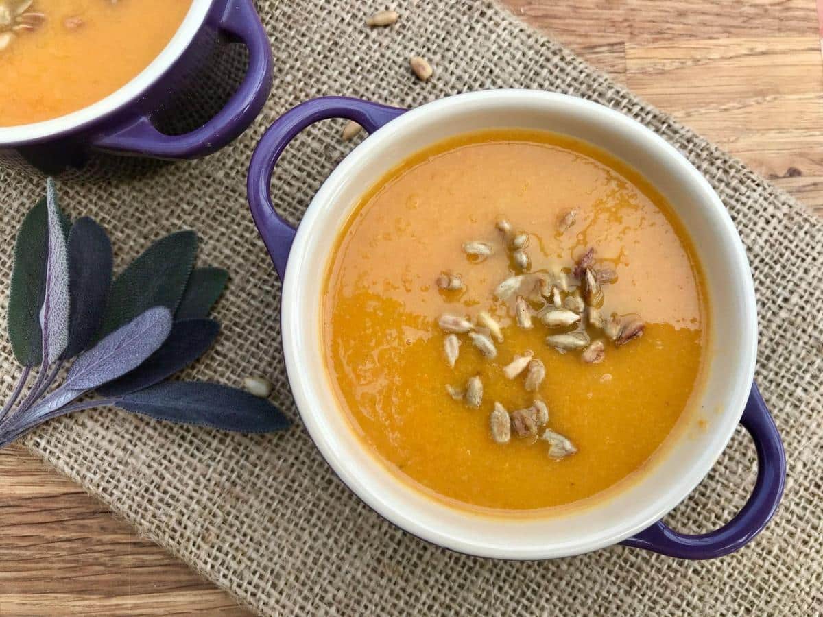 Healthy carrot and apple soup in bowl on hessian.