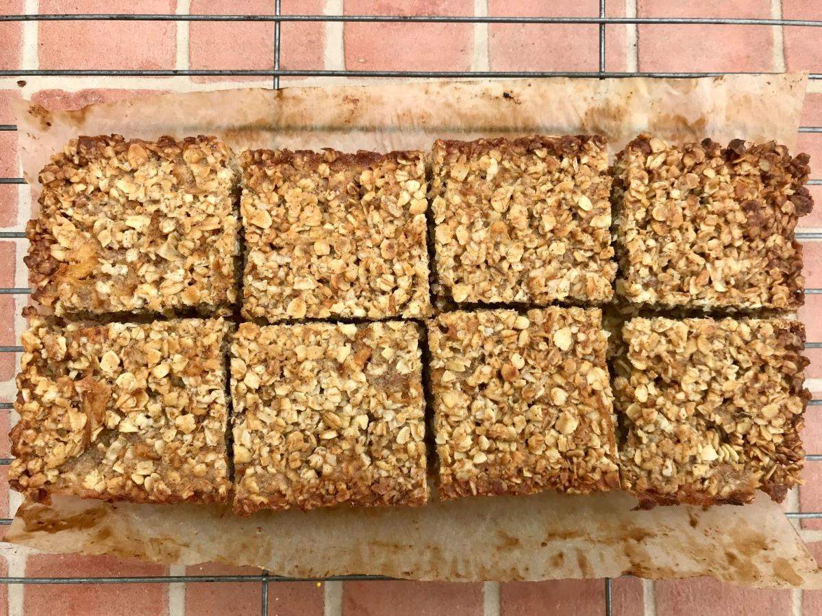 Oat bar squares on paper on wire rack.
