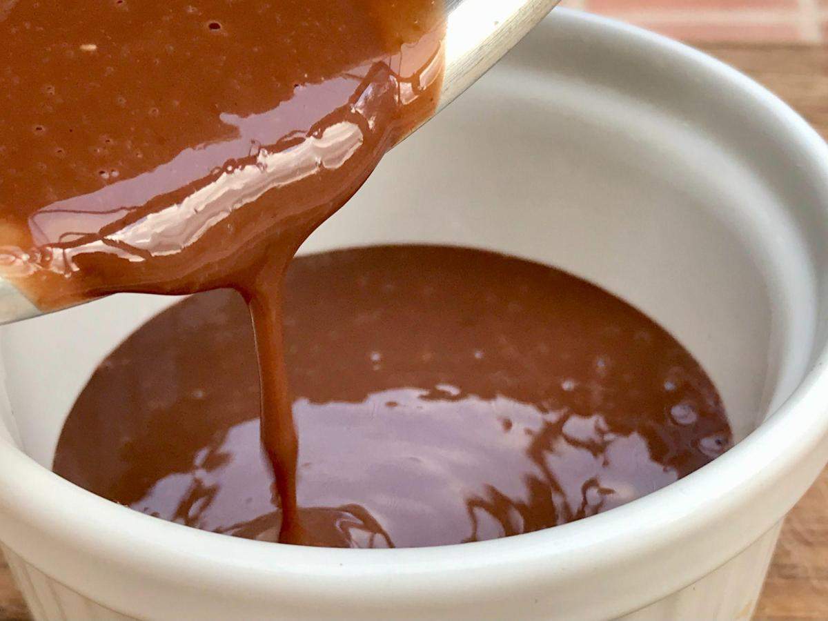 Pouring low calorie chocolate sauce from pan into bowl.