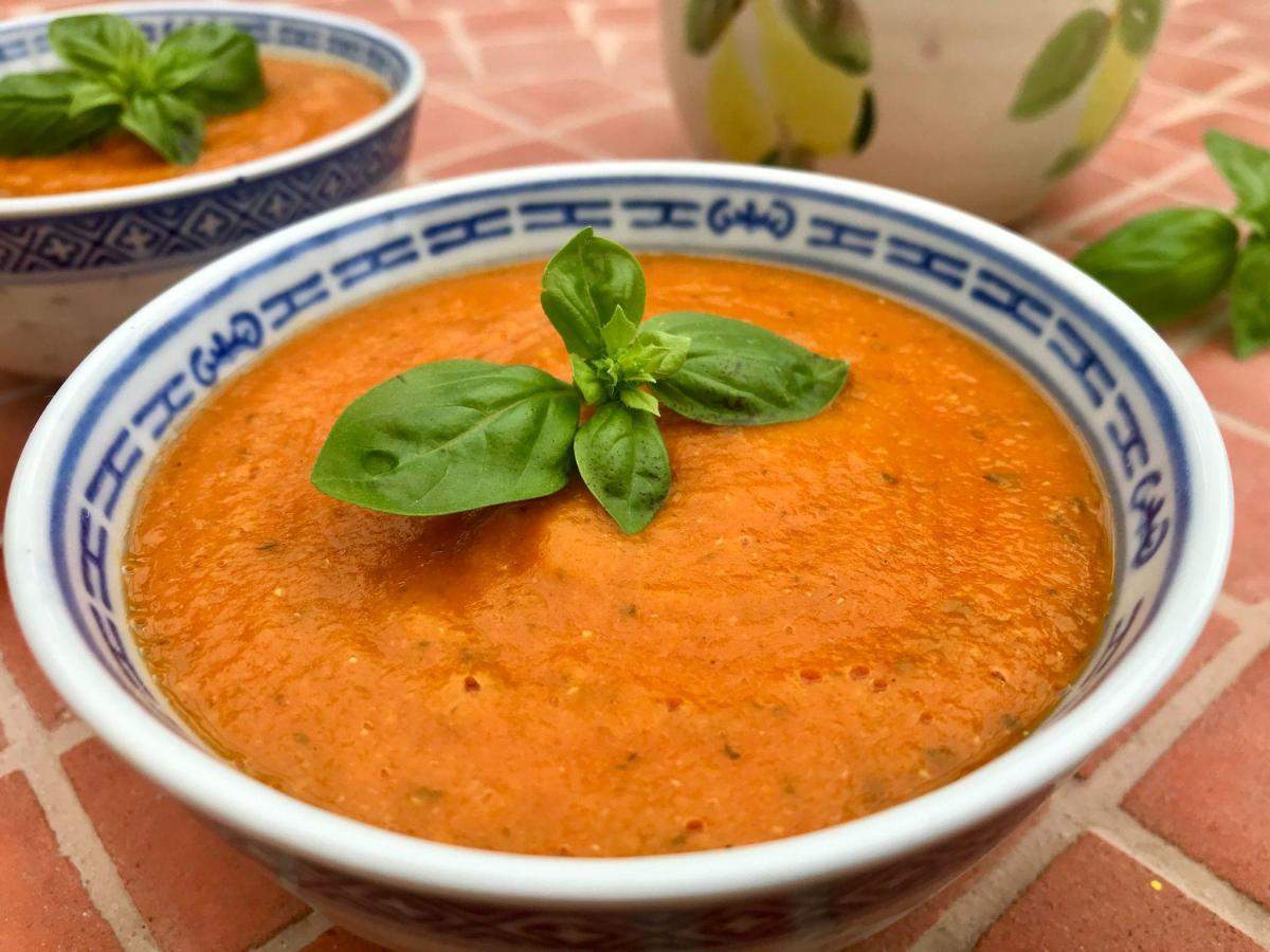 Tomato red lentil soup on tiled worktop with olive oil.