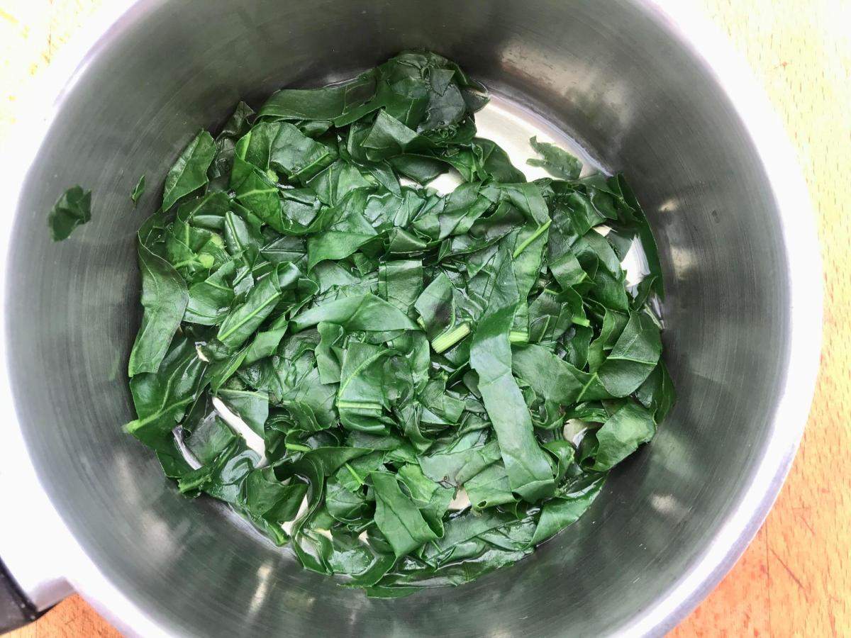 Wilting perpetual spinach leaves in a pan.