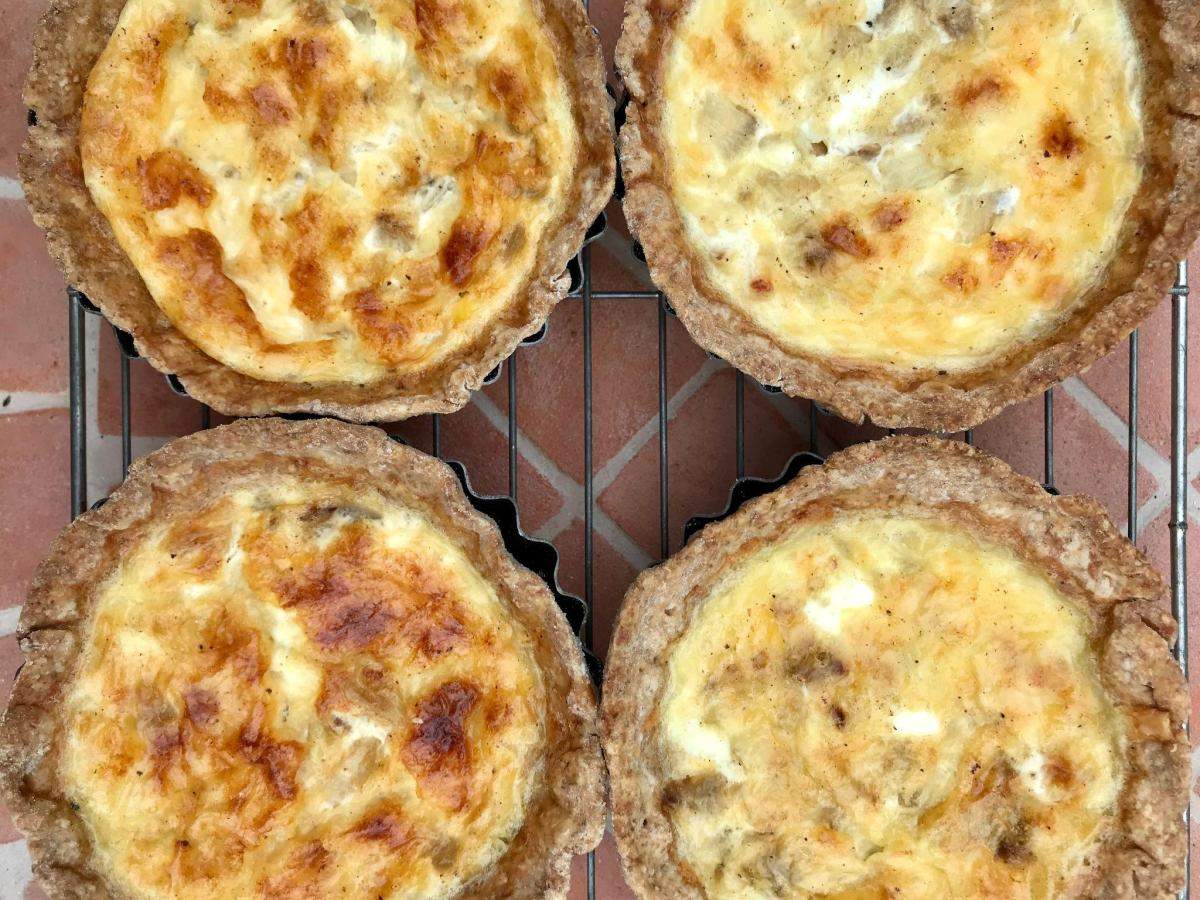 Mini cheese and onion quiche on wire rack.