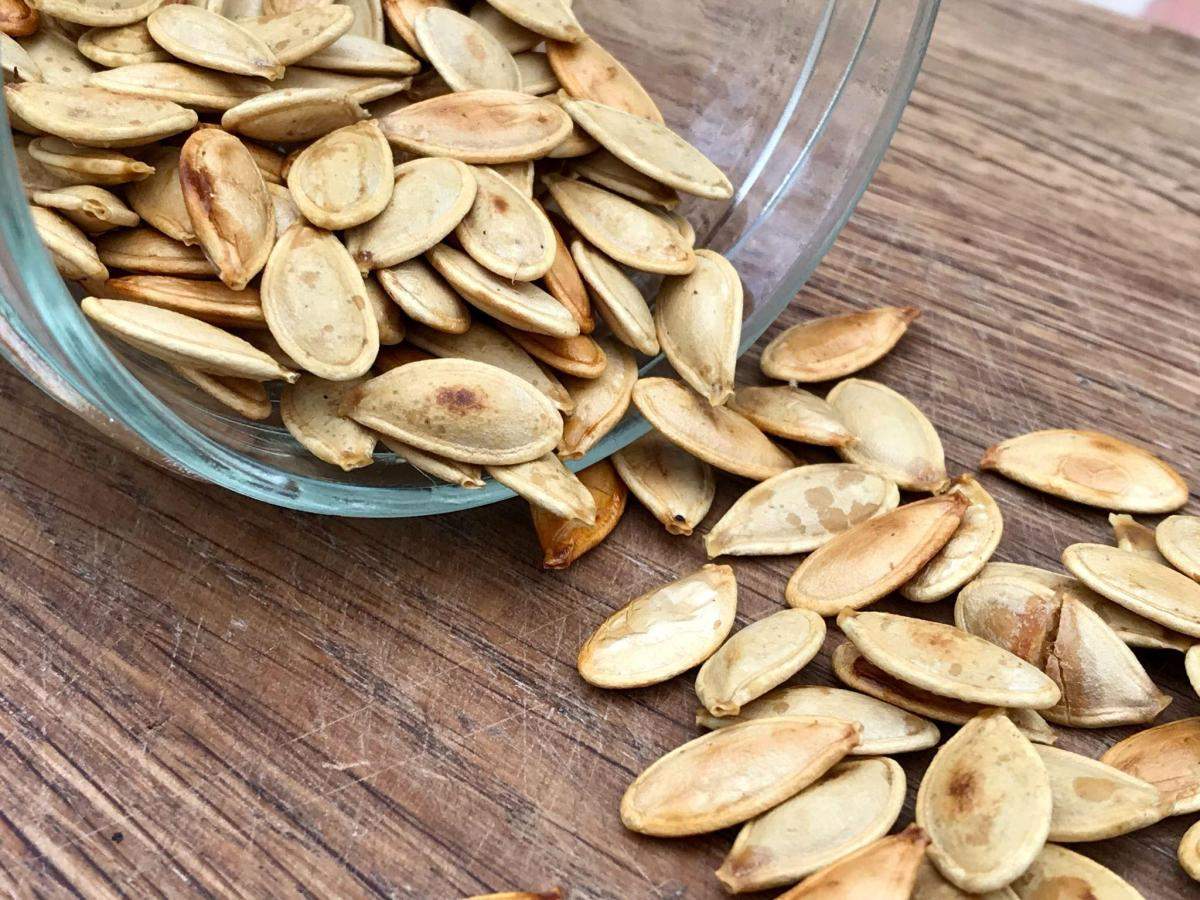 Roast pumpkin seeds tipping out of jar.