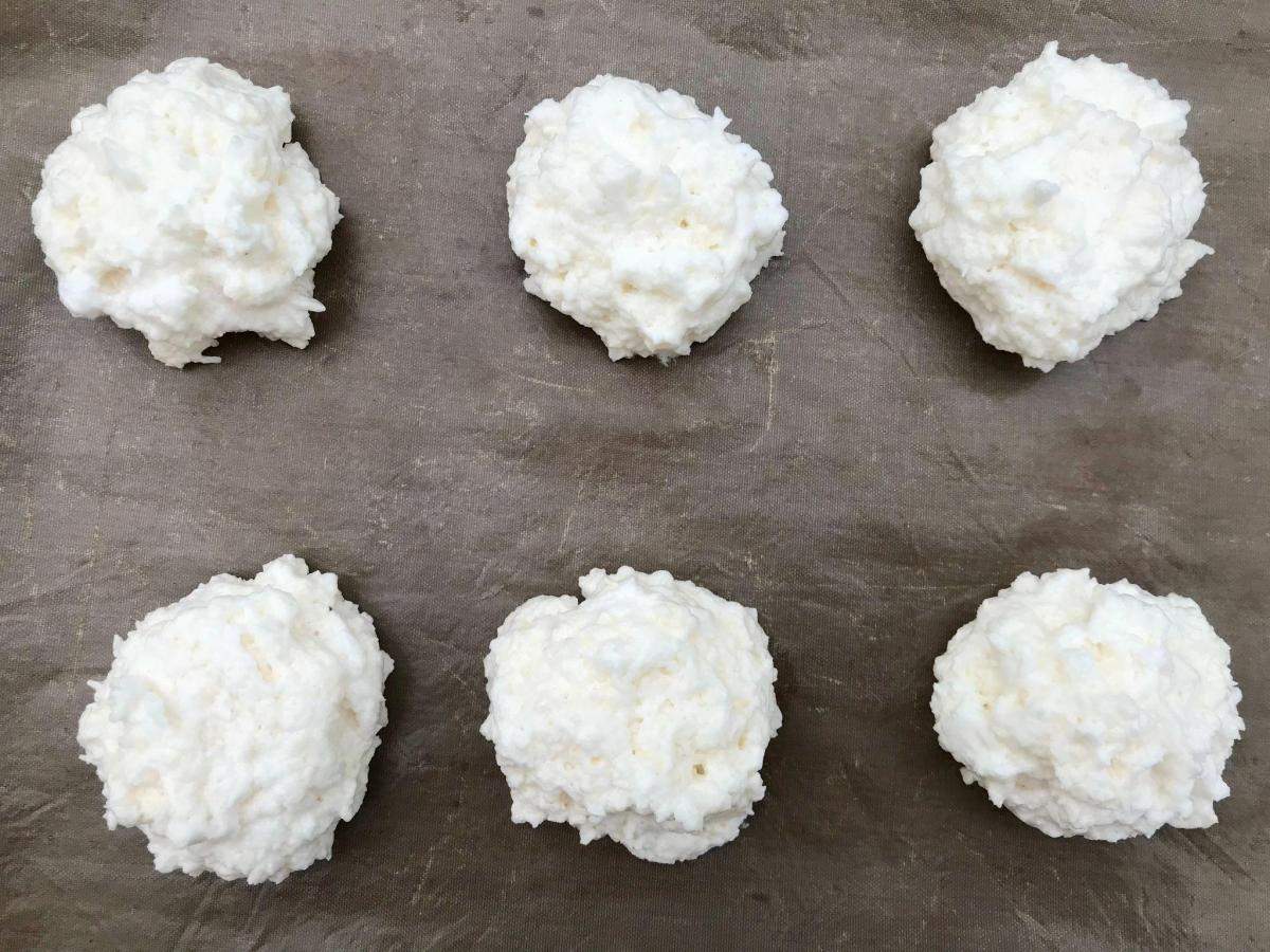 Spoonfuls of coconut macaroon mixture on tray.