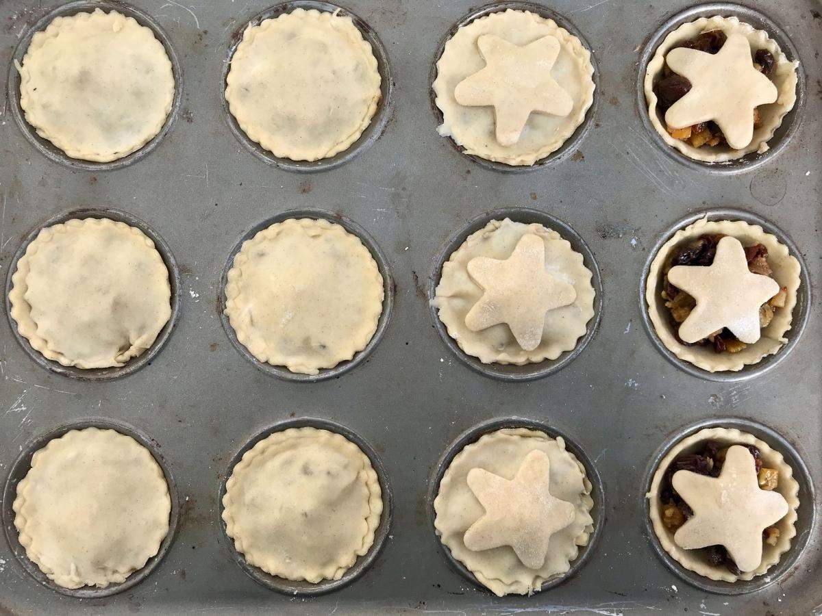 Uncooked mince pies in baking tin.