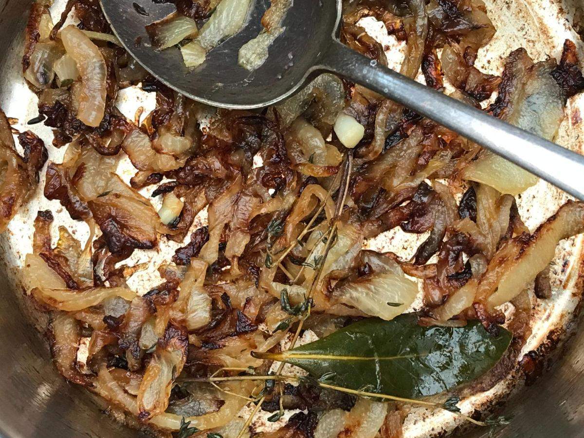 Caramelised onions in pan with herbs.