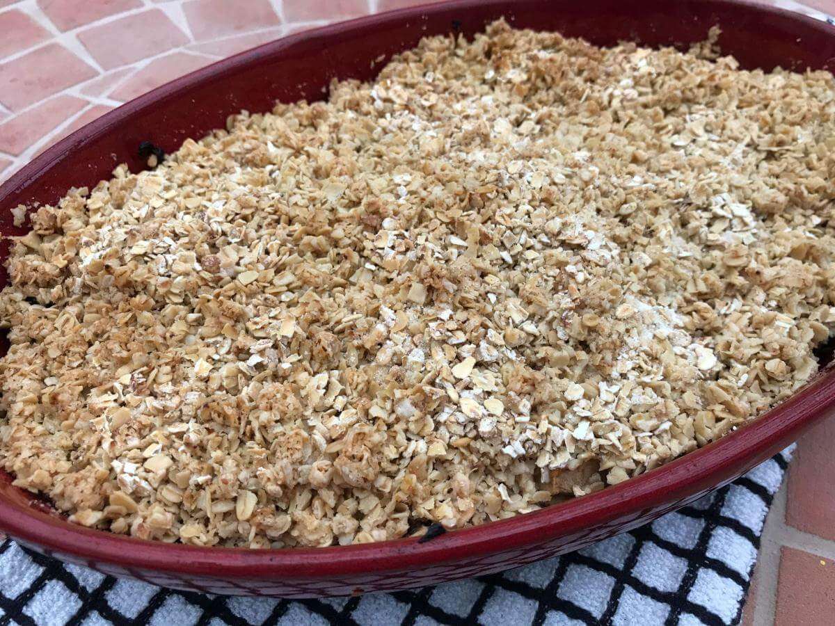 Cooked apple and mincemeat crumble in red dish.