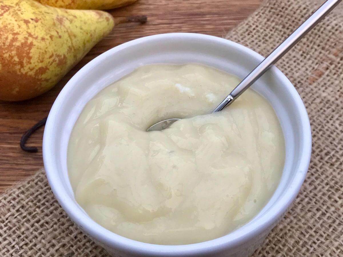 Dairy free custard sauce in white bowl with spoon.