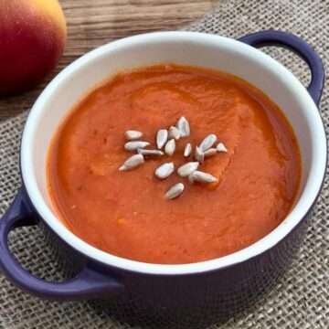 Sweet potato and red pepper soup in purple handled dish.