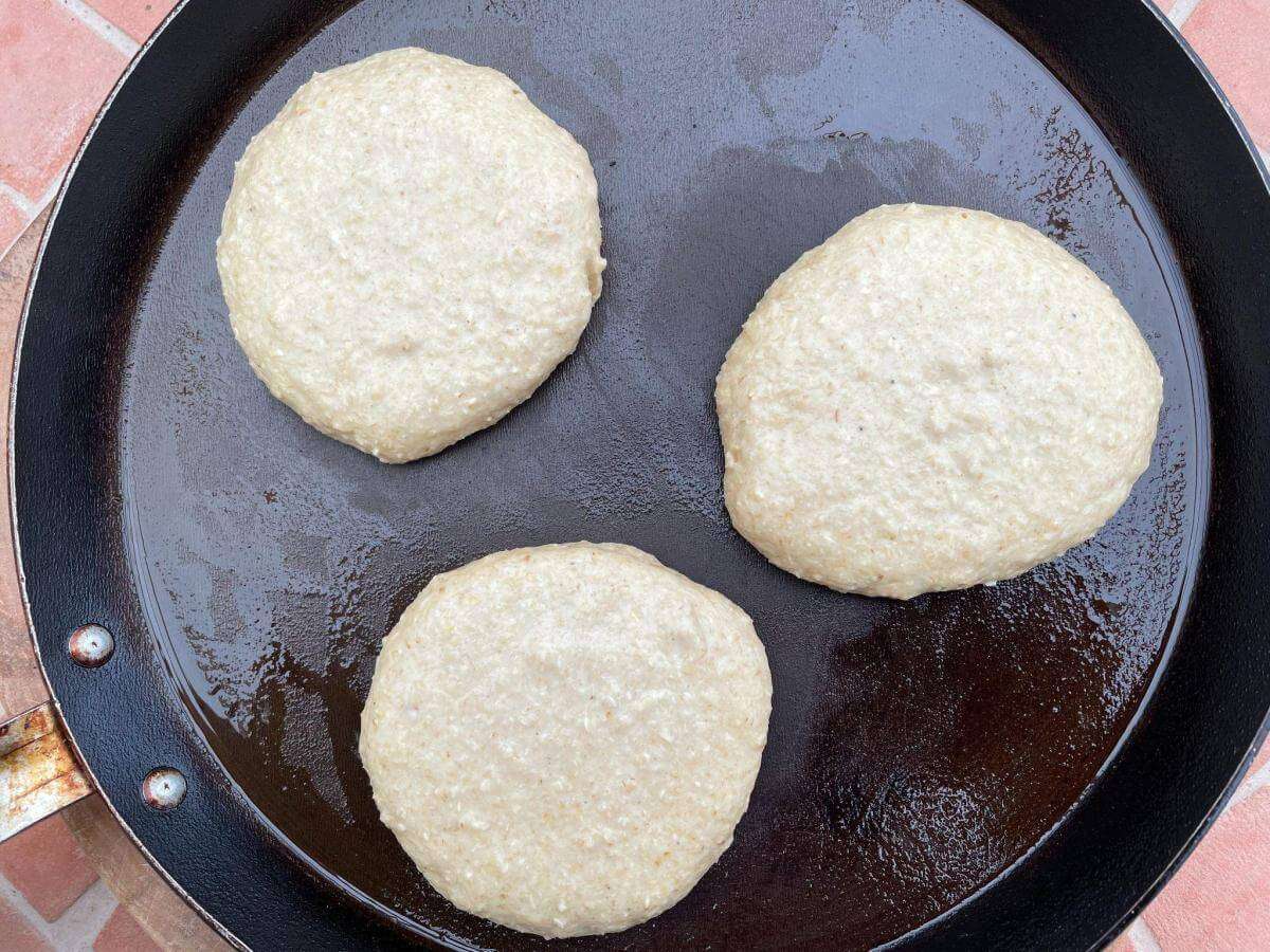 Fluffy oat flour pancakes cooking in pan.