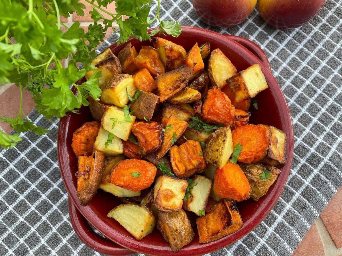 Roast sweet potatoes and carrots in red dish.