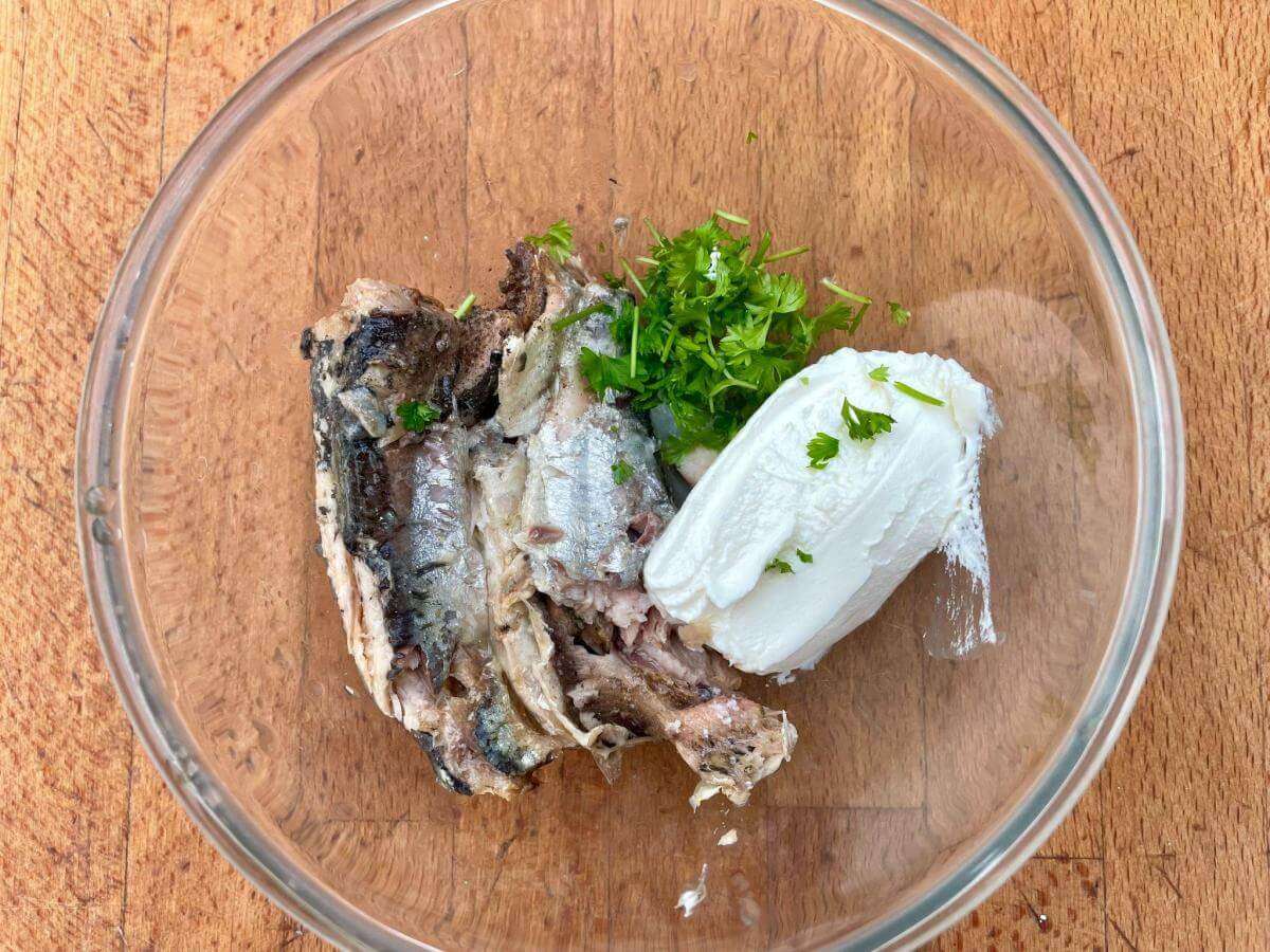 Canned sardines, cream cheese and parsley in bowl.
