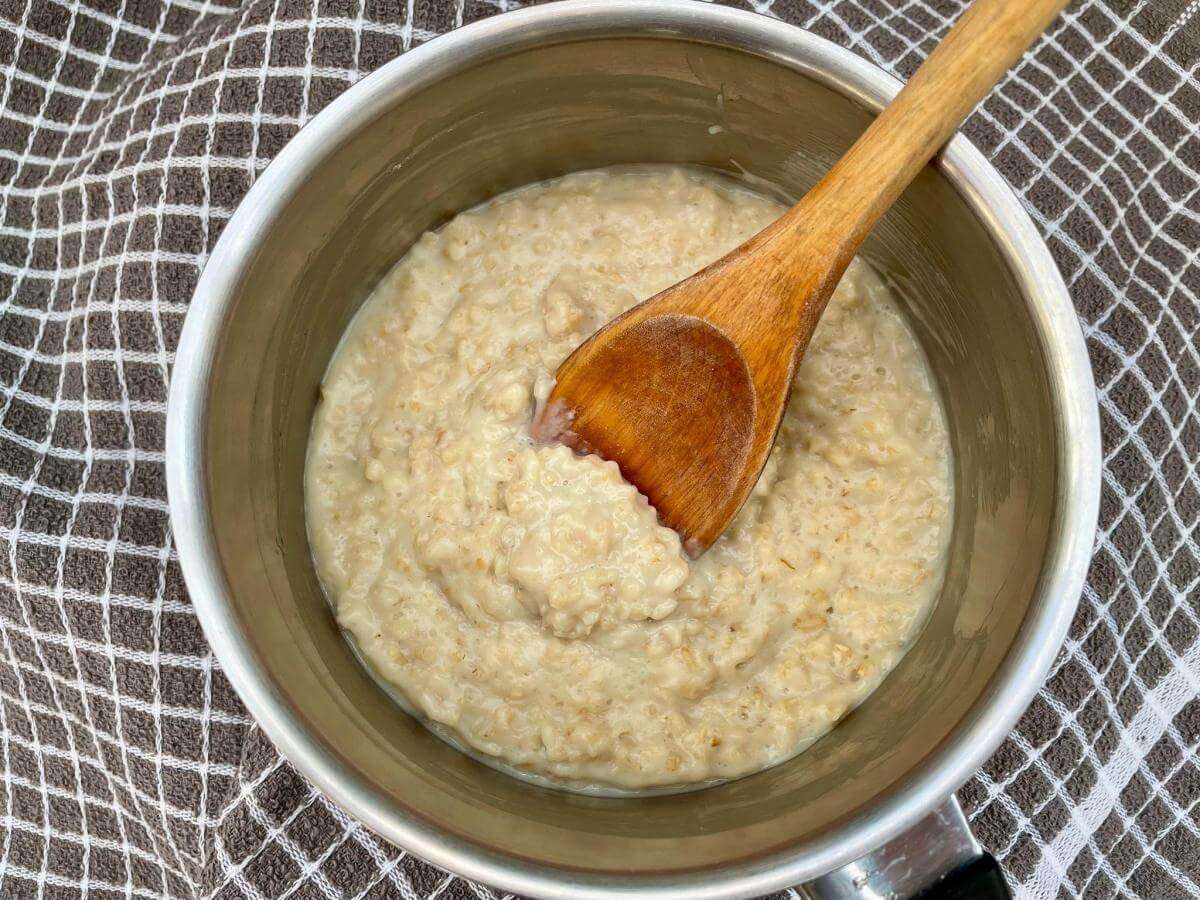 Dairy free porridge in pan with wooden spoon.