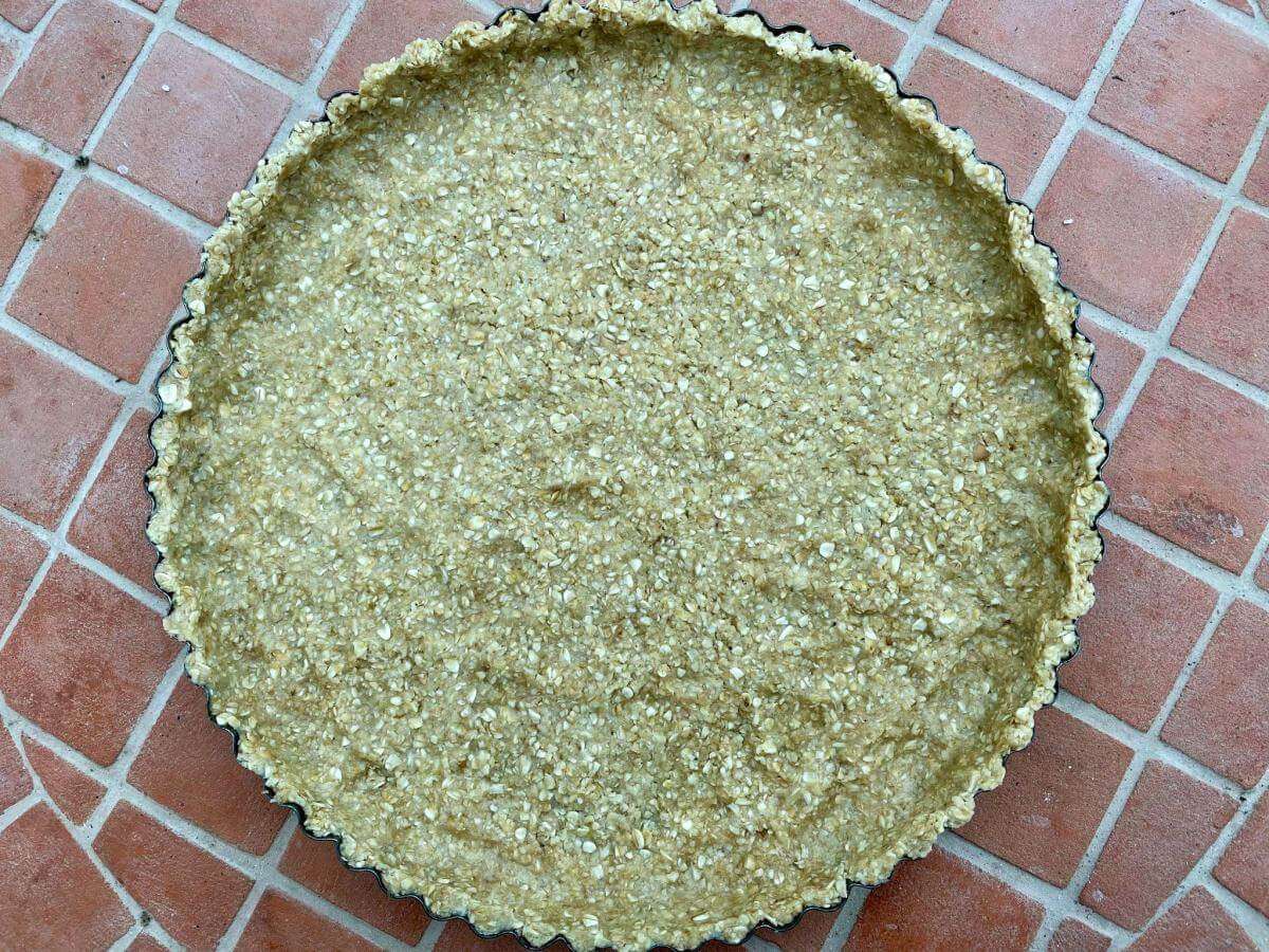 Uncooked oatmeal pie crust in baking tin.