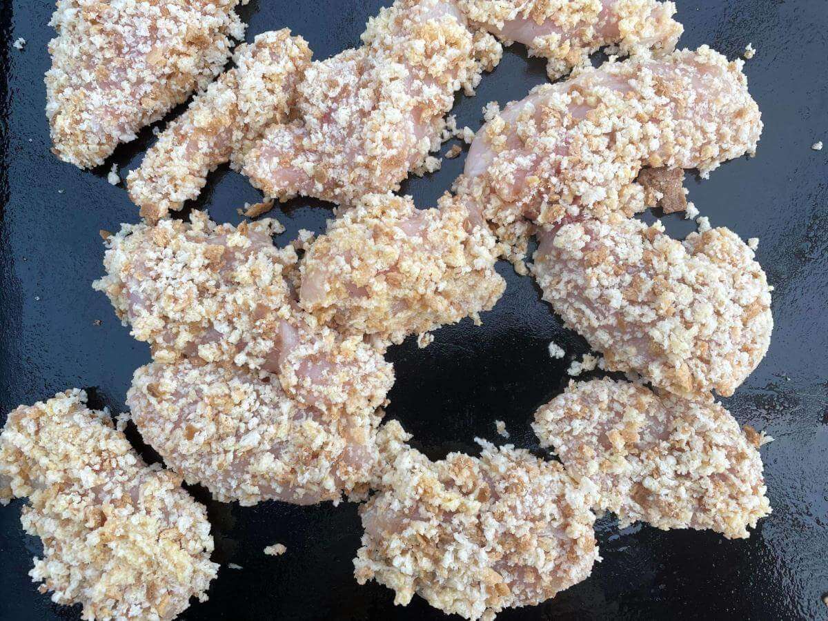Uncooked chicken goujons on tray.