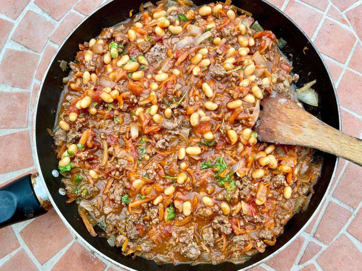 Beef stew with baked beans in pan.