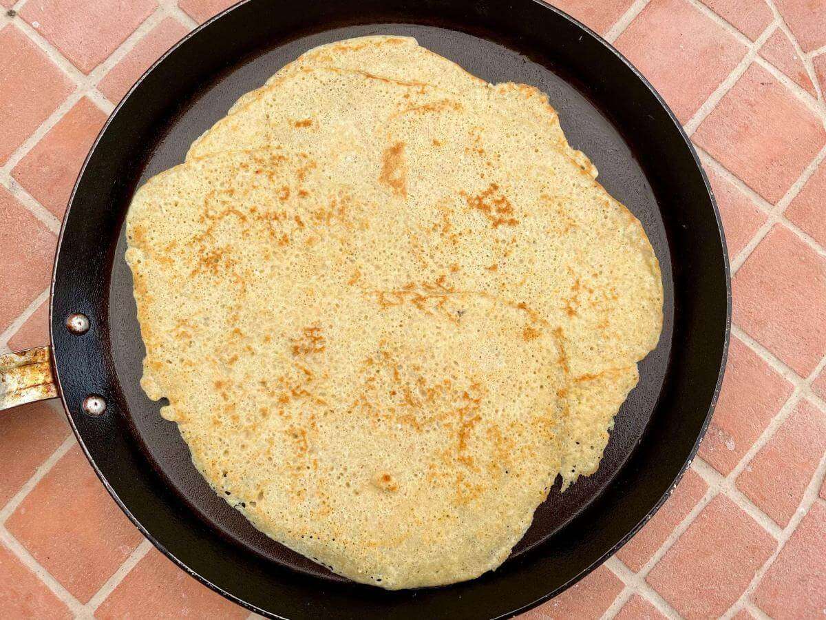Thin oat milk pancake in pan.