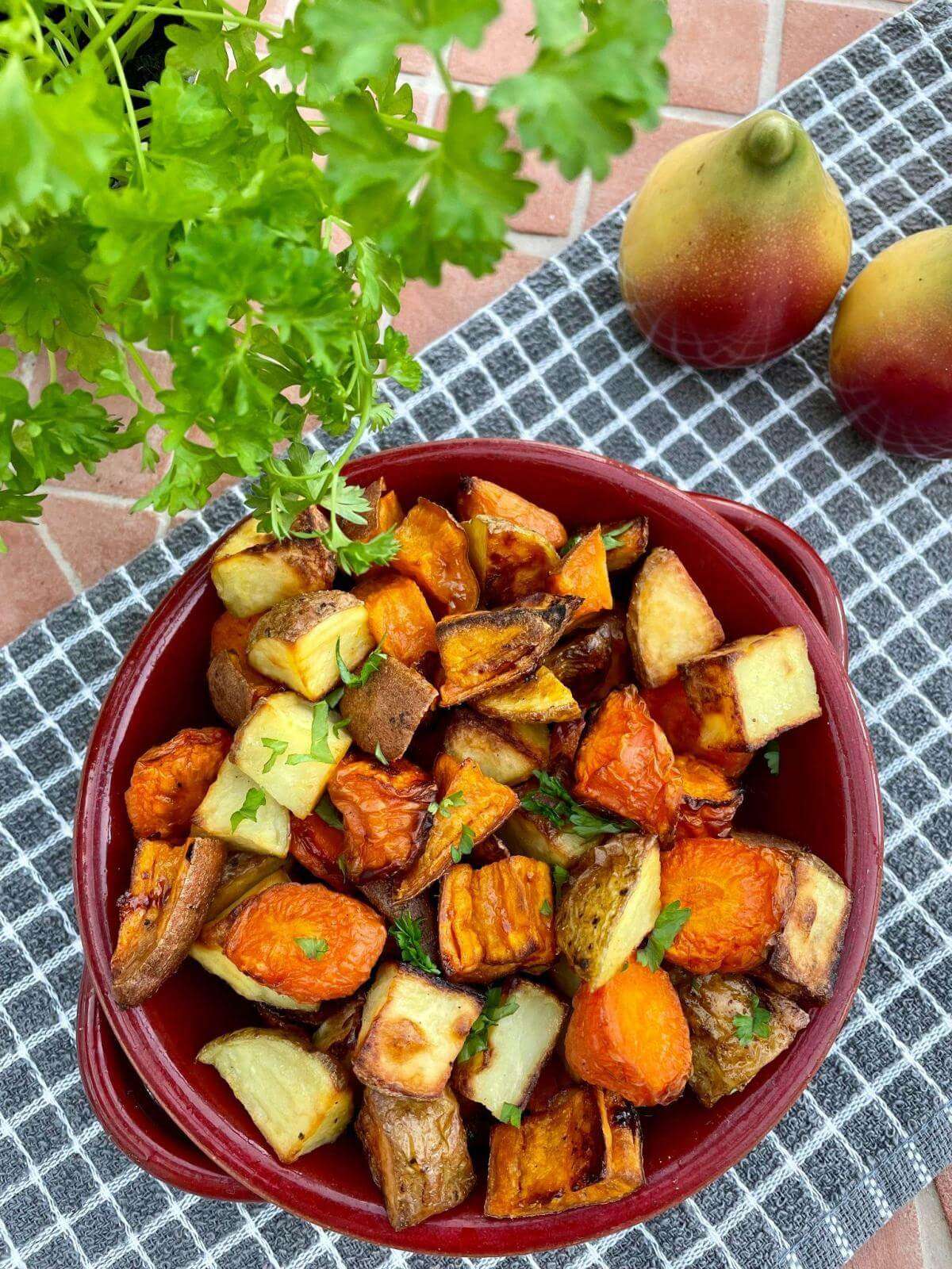 Roast vegetables in red dish with parsley.