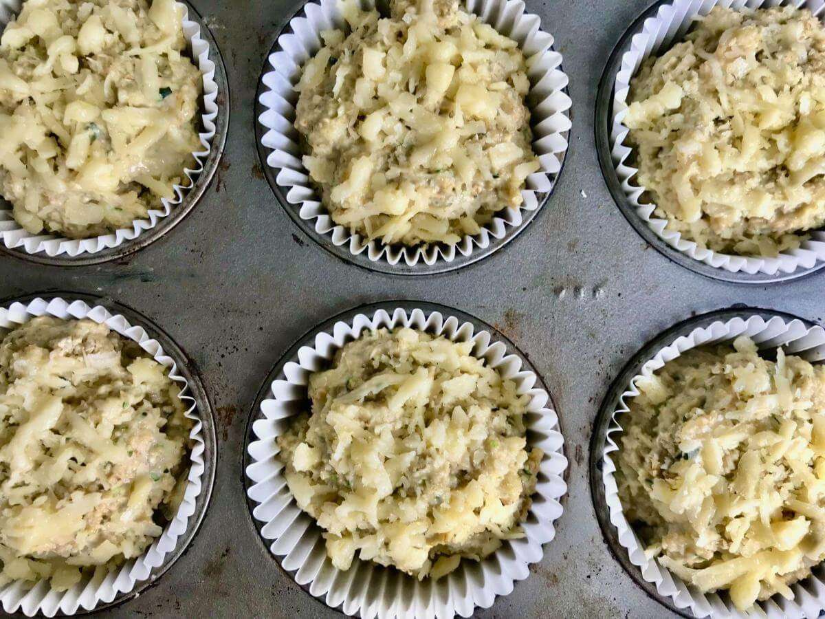 Uncooked savoury zucchini muffins in tin.