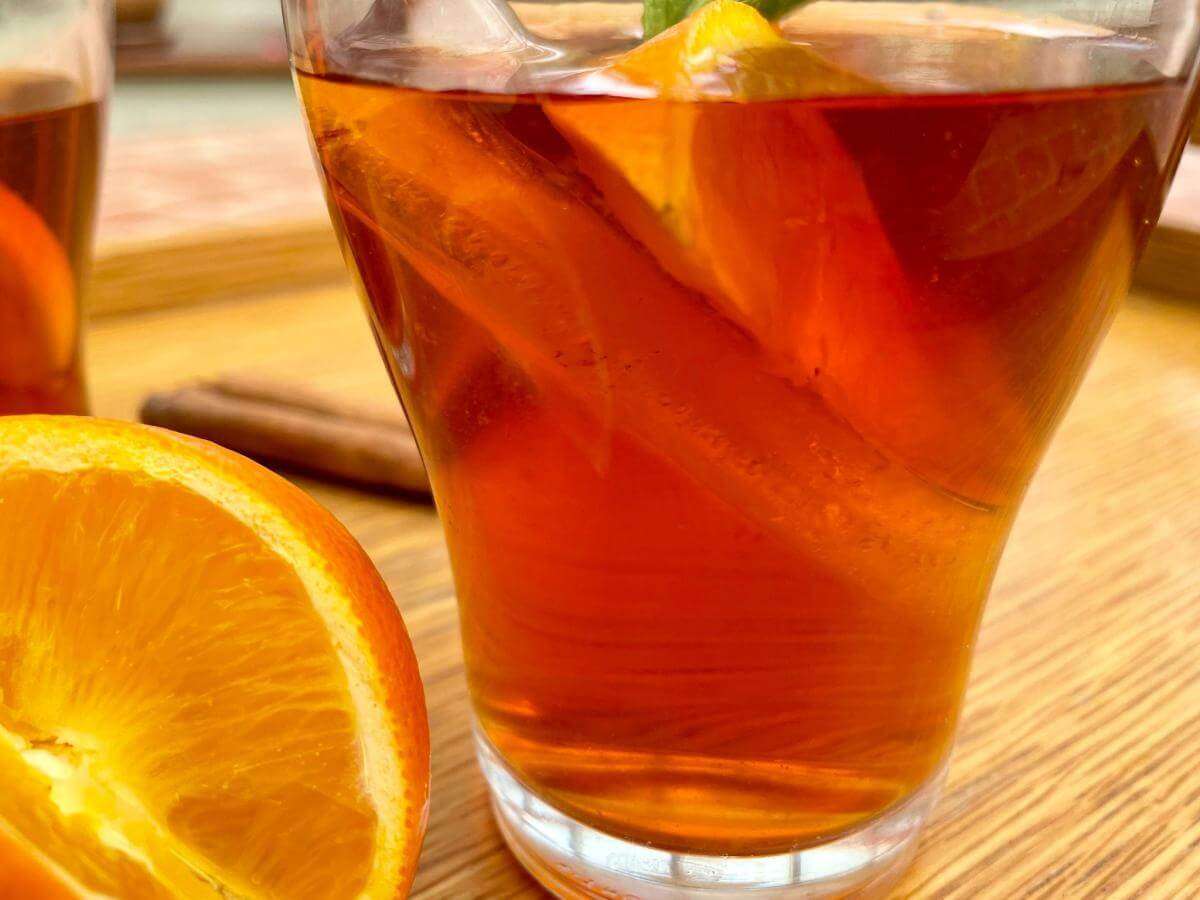 Iced rooibos tea in glass with orange slice and ice.