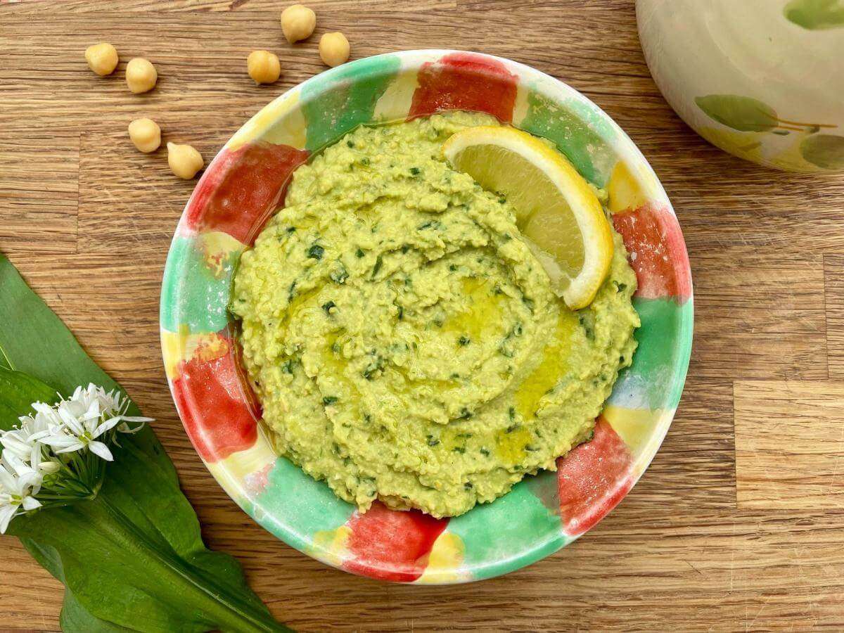 Wild garlic and chickpea dip on wooden board.