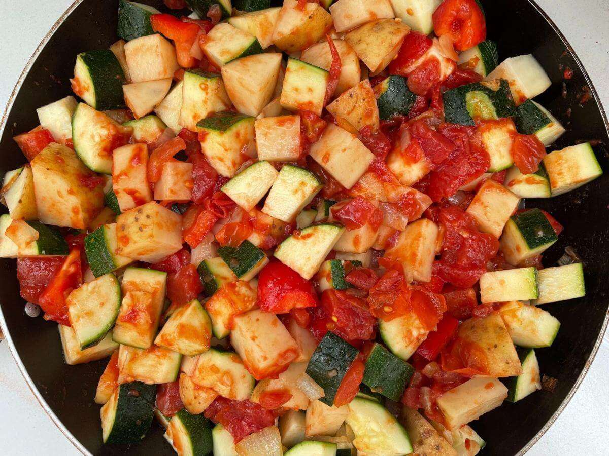 Zucchini, pepper, potato and tomato in pan.