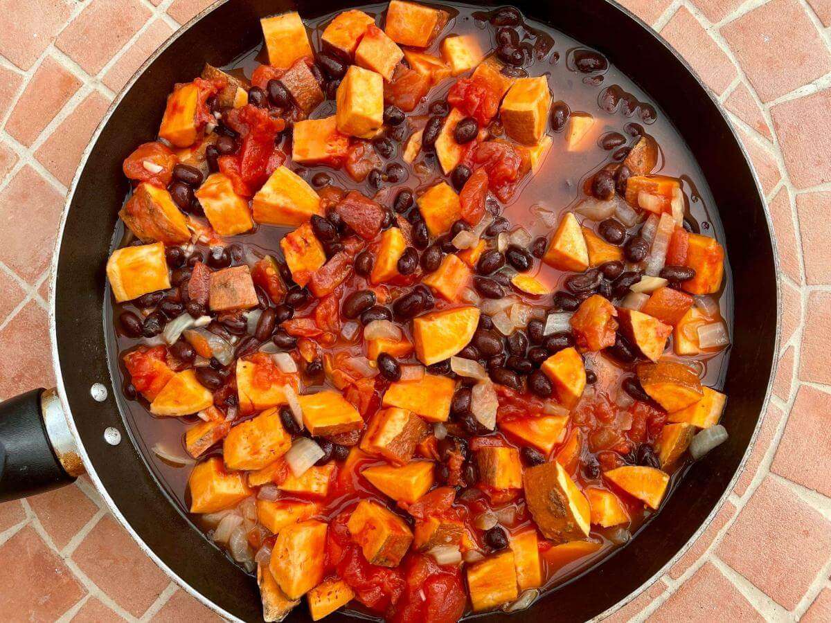Black beans, tomato and sweet potato in pan.