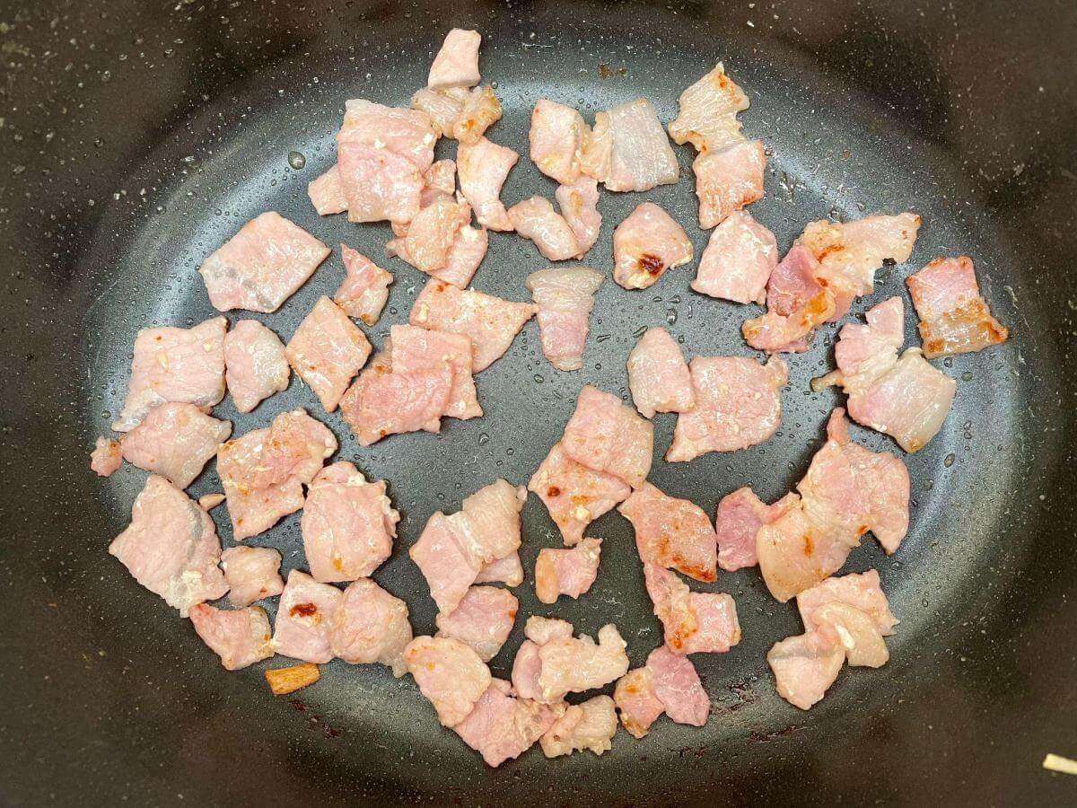 Fried bacon cubes in pan.