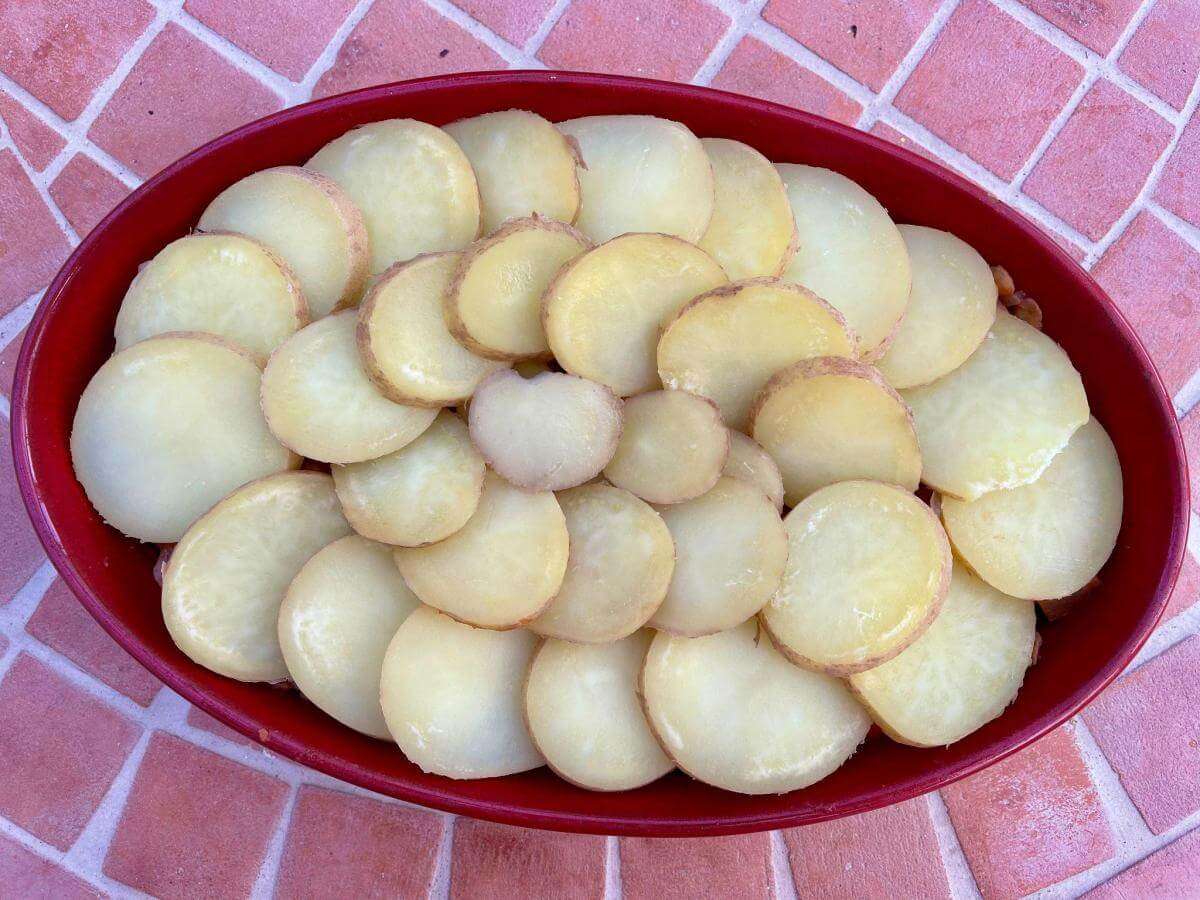 Cooked sliced potatoes arranged on lentil stew.