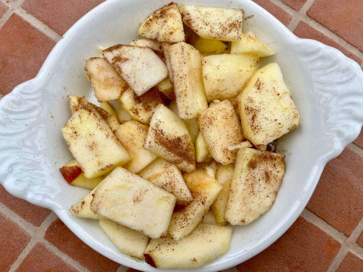 Peeled and sliced apple in dish with cinnamon.