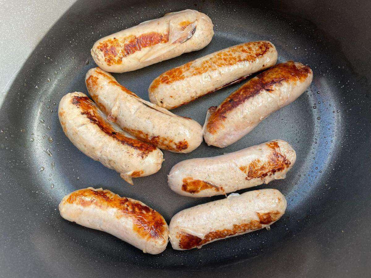 Browned sausages in pan.