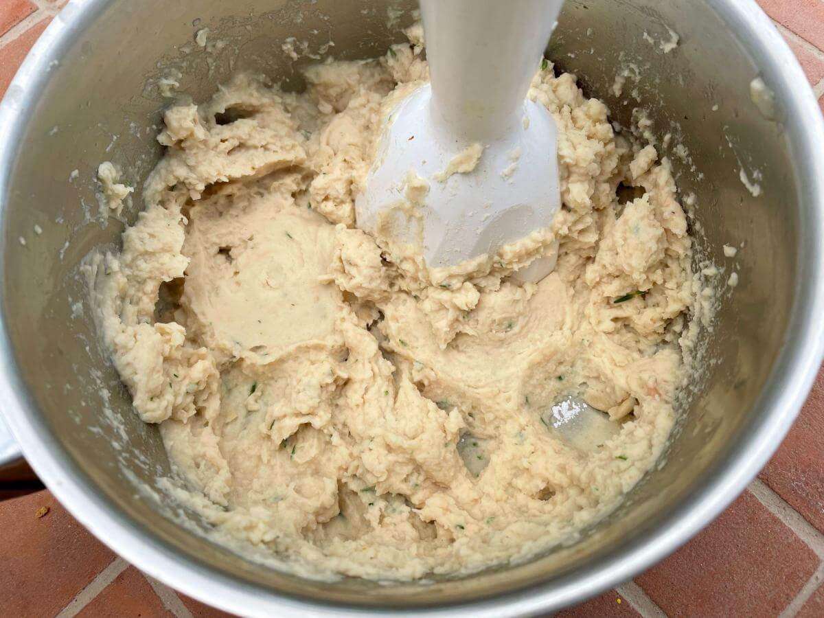 Blitzing bean puree in pan with immersion blender.