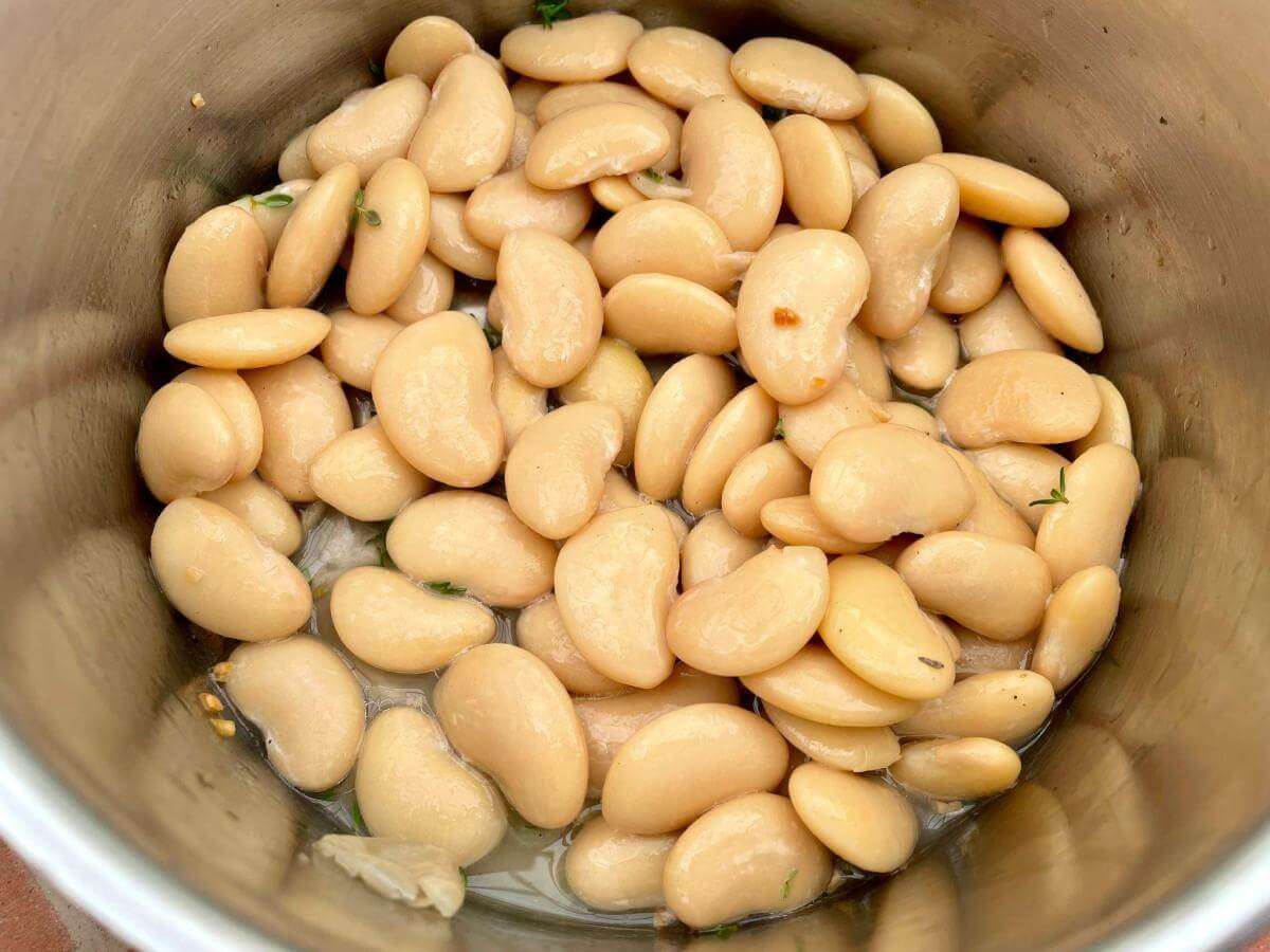 Butter beans garlic and herbs in pan.