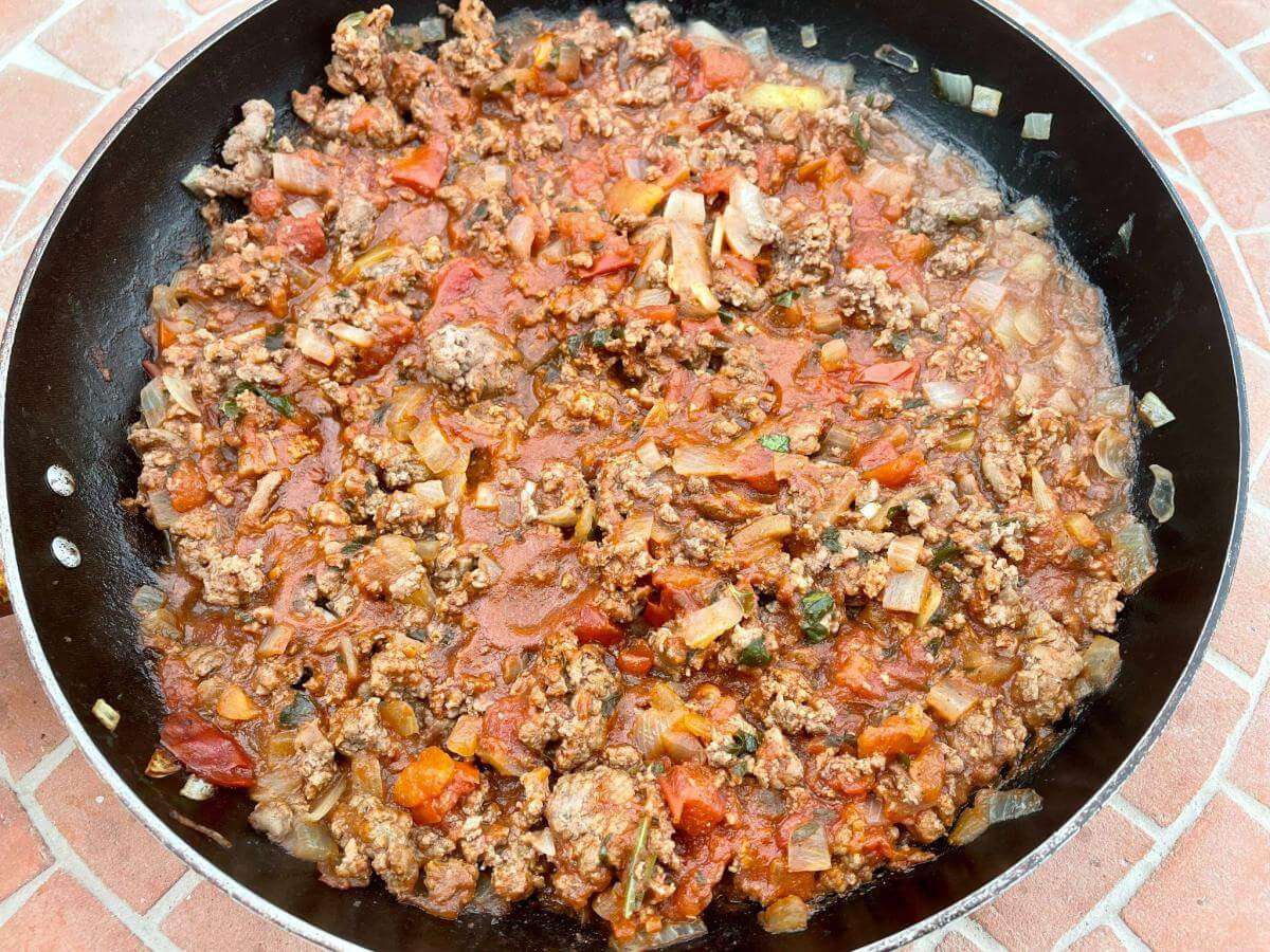 Meat sauce with minced beef, tomatoes and onions in pan.