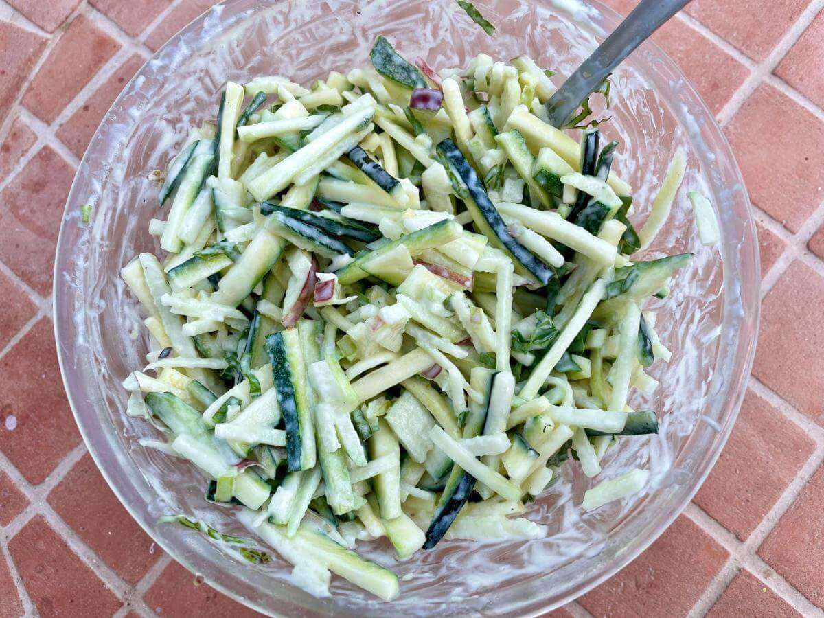 Courgette and apple slaw in mixing bowl.
