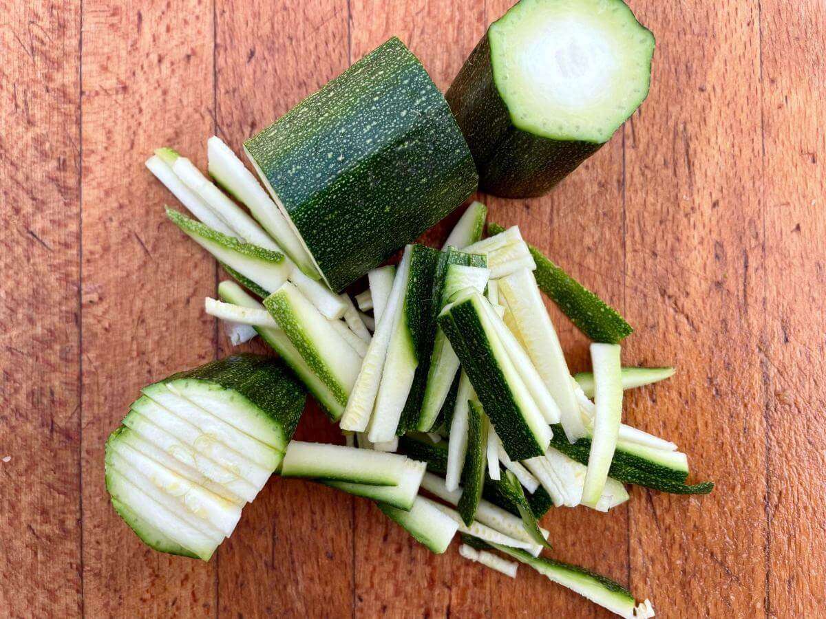 Courgette matchsticks on chopping board.
