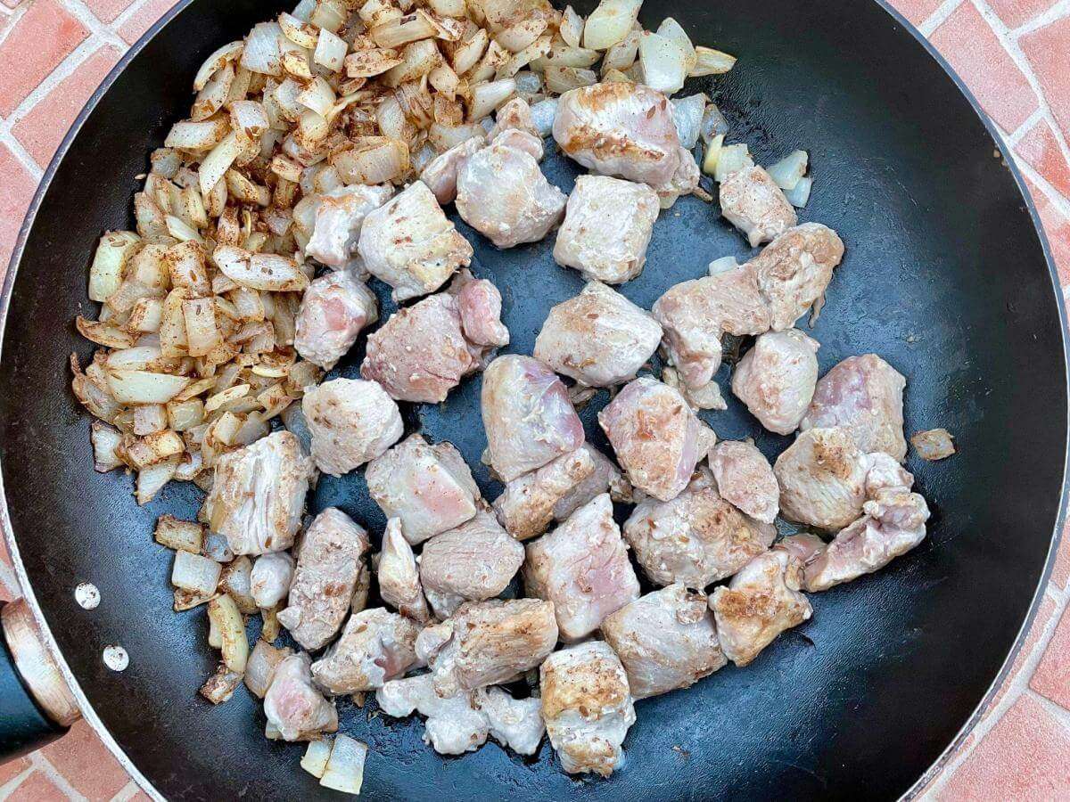 Browned onions and pork in pan.